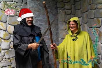 Kaksi iloista pikkujoulun viettäjää pakohuoneessa viitat päällä