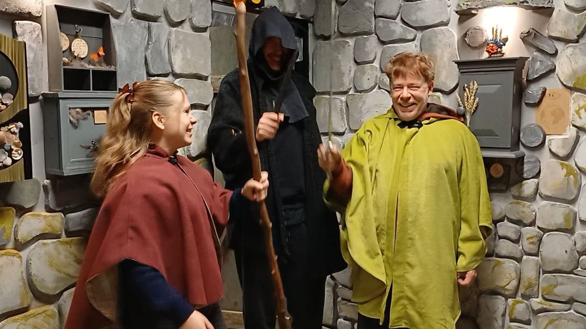 Joukko iloisia pelaajia viitat yllä pakohuoneessa, joka näyttää kiviseinäiseltä holvilta. Joukko iloisia pelaajia viitat yllä pakohuoneessa, joka näyttää kiviseinäiseltä holvilta.